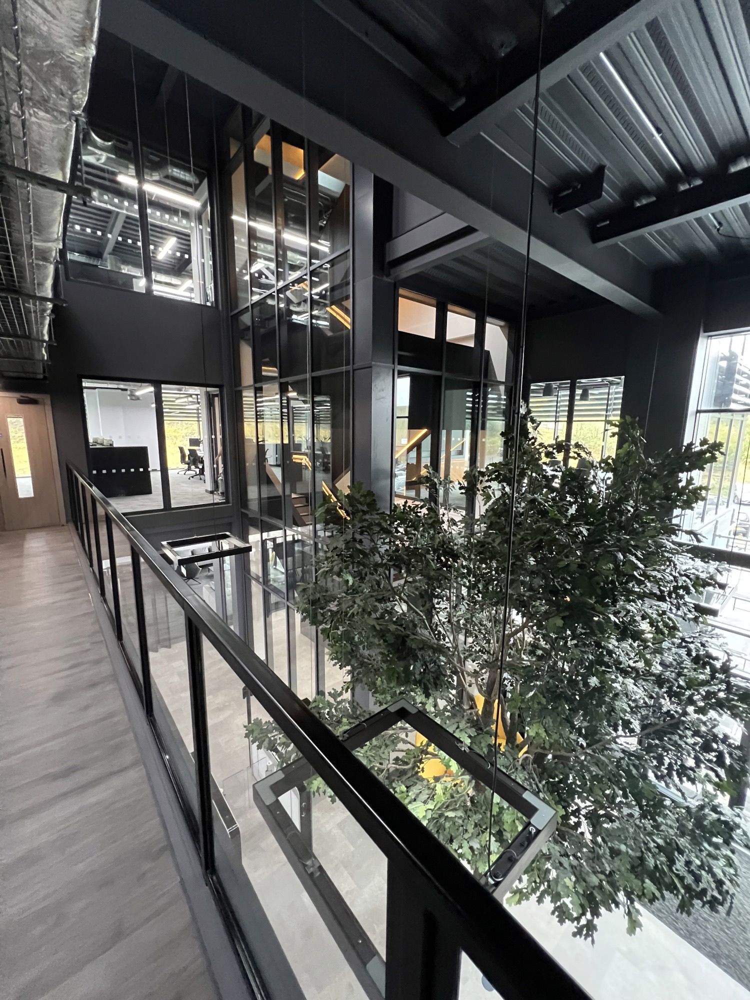 Modernes Bürogebäude mit künstlichem Baum und Treppenhaus eingeglast